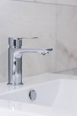 İçinde bir damla su ve gri fayanslardan oluşan bir lavabo olan bir musluk. Tadilattan sonra tuvaletin içinde. Su kavramı kaydediliyor.