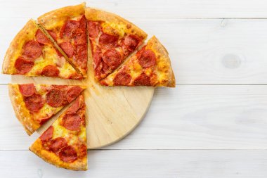 Ahşap bir masada pepperonili pizza dilimleri. Yatay yönelim, üst görünüm, kopyalama alanı.