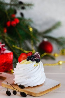 Noel ağacının arka planında Pavlova tatlısı. Kremalı pasta..