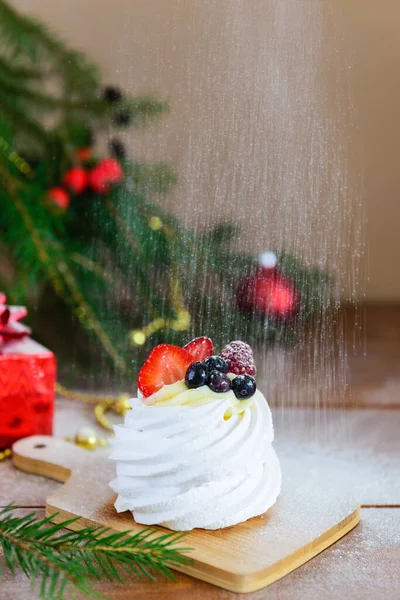 Pavlova Dessert Mit Fallendem Puderzucker Auf Dem Hintergrund Eines Weihnachtsbaums — Stockfoto