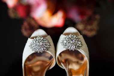 Açık burunlu hafif düğün ayakkabıları üzerinde beyaz şeffaf kristaller ile büyük tokalar. Koyu bulanık arka plan.