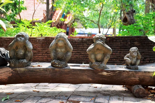 Три статуи обезьяны сидят на фоне природы и руки небольшой статистики — стоковое фото