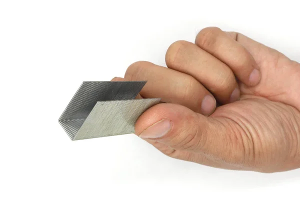 Мужская рука, держащая металлические скобы для степлеров, изолированных на белом ba — стоковое фото