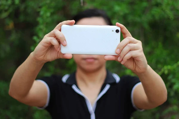 Asyalı kadın tutarak ve akıllı telefon gösterisi arka tarafı kullanarak.