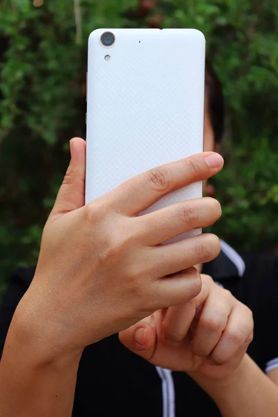 Asiatische Frau halten und mit Smartphone zeigen Rückseite. — Stockfoto