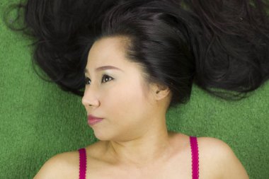 Yeşil çimenlerin üzerinde uzanan kadınlar, güzel ve komik bir gülümseme sergiliyorlar.