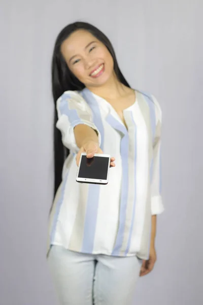 Lächelnde Frauen, die ihr Handy in der Hand halten, geben Ihnen ein Smartphone. i — Stockfoto