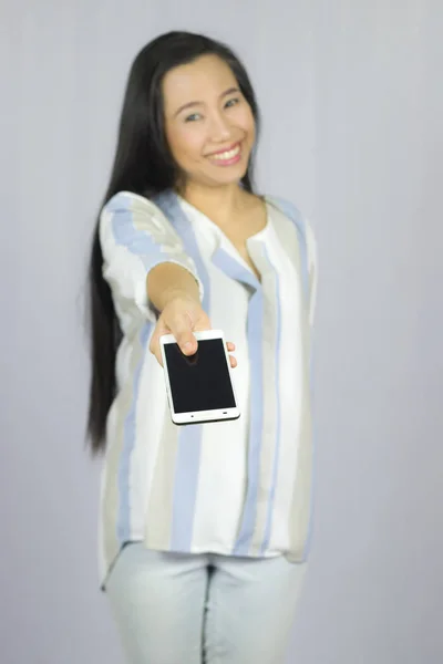 Lächelnde Frauen, die ihr Handy in der Hand halten, geben Ihnen ein Smartphone. i — Stockfoto