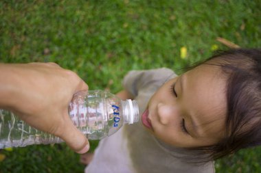 küçük çocuklar yeşil parkta şişeden su içme.