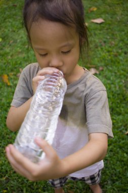 küçük çocuklar yeşil parkta şişeden su içme.