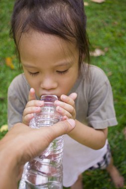 küçük çocuklar yeşil parkta şişeden su içme.