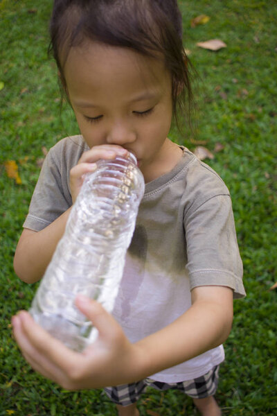 маленькие дети пьют воду из бутылки в зеленом парке
.