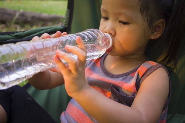 маленькие дети пьют воду из бутылки в зеленом парке
.