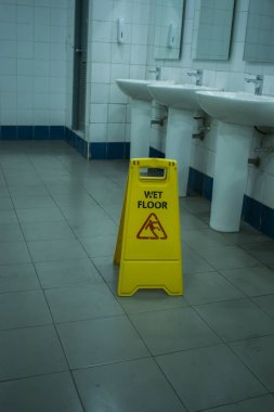 Yellow slippery warning sign, caution wet floor sign in the toil
