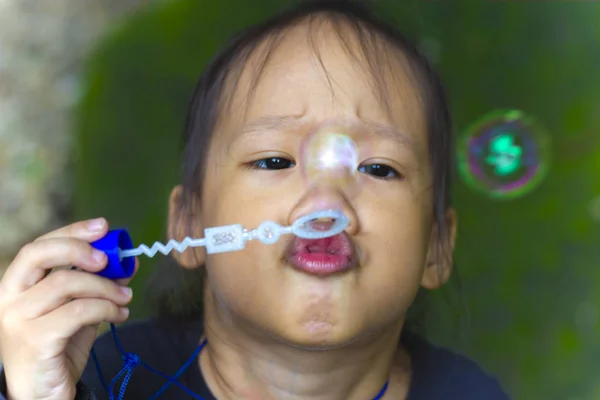Asian little boy is blowing a soap bubbles, Outdoor Portrait