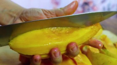 Genç kadın mangotemizler ve keser. Kız mango soyma ve elinde tutun, bıçakla kesme. olgun mango soyma, olgun mango ve soymak için kullanılan paring bıçak arka planda.