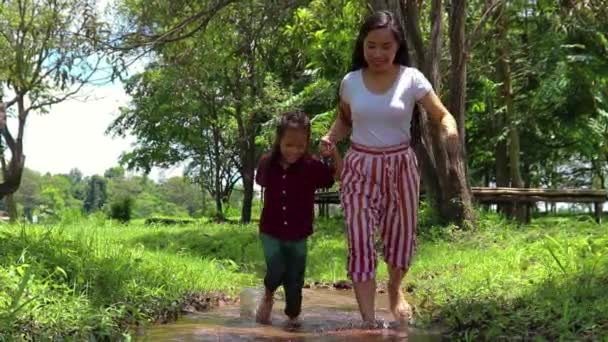 Mãe e crianças brincando descalços na água do córrego, jogar lama e correr . — Vídeo de Stock