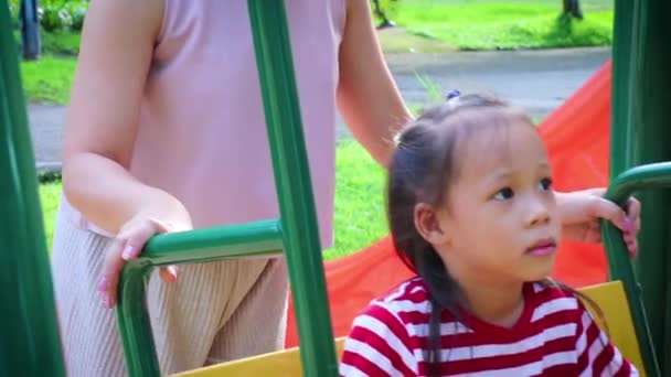 Aziatische gelukkig moeder duwen lachende zoon op schommel in een park. — Stockvideo