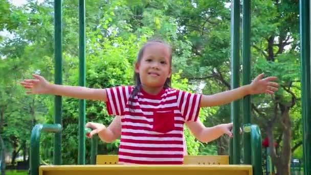 Asiático feliz mãe empurrando rindo filho no balanço em um parque . — Vídeo de Stock