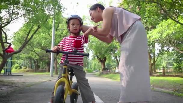 어머니 도움 그녀의 아들 (긴 머리 소년) 야외에서 자전거 헬멧에 넣어. — 비디오