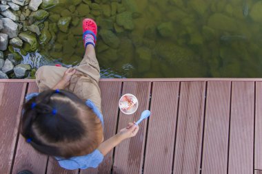 Küçük çocuklar suya bakar lar ve tahta br'de balıkları beslerler.