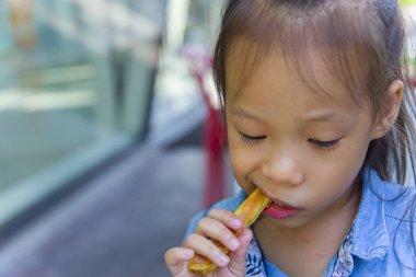 Sevimli asya uzun saç çocuk gülümseyen ve ekmekli st yemek zevk