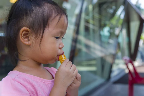 Adorable asian child smiling and enjoy eating breaded sticks at
