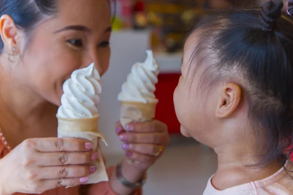 Mom and little child eating ice scream cone  together . feeling