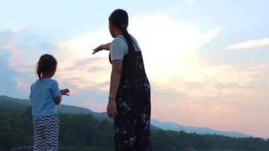 Annem çocukları geride bırakıp gün batımında göle bakıyor. Doğada, tatilde, açık havada genç bir ailenin portresi. Aile tatili kavramı.