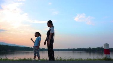 Annem çocukları geride bırakıp gün batımında göle bakıyor. Doğada, tatilde, açık havada genç bir ailenin portresi. Aile tatili kavramı.