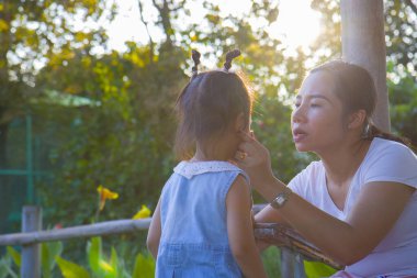 Genç anne ağlayan küçük kızını sakinleştiriyor, Asyalı anne dene