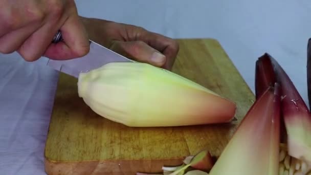バナナの花の皮をむいた男の手料理やサラダのためのバナナの芽を準備. — ストック動画