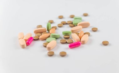 turuncu pembe yeşil yuvarlak uzun hapları ve beyaz bir arka plan üzerinde sağlık için vitamin kapsülleri