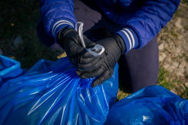 doğada çöp, mavi büyük plastik torba ya tek lateks eldivençöp nehir üzerinde ilkbaharda çevre temizliği