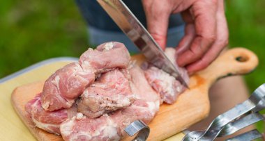 Erkek ellerinin yakın çekim keskin bir metal bıçak ile parçalara marine çiğ et dilimlenmiş