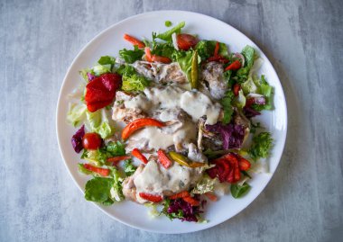 Sebze ve çilekle servis edilen kremalı sosta pişirilmiş tavşan.