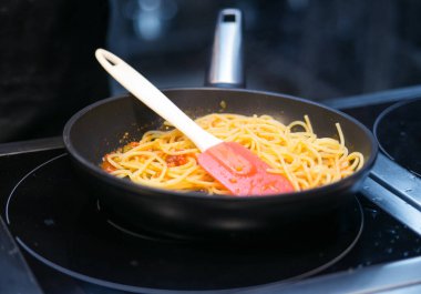 Kızartma tavasındaki spagetti, silikon bir kürek.