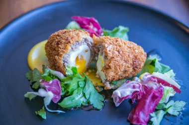Kıymalı skoç yumurtası ve sebze tabakta servis edilir.