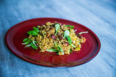 Kırmızı tabakta servis edilen deniz mahsullü risotto.