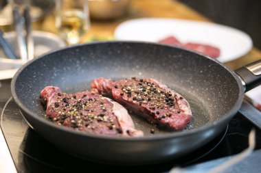Çiğ biftek mutfakta tavada kızarır.