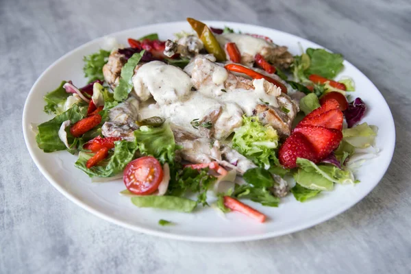 Sebze ve çilekle servis edilen kremalı sosta pişirilmiş tavşan.