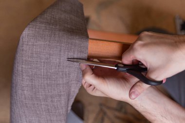 Adam sandalyeyi yeniler, sandalyenin yumuşak yüzeyini yeni bir kumaşla kaplar.