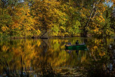 Güzel sonbahar manzarası göl balıkçılarının balık tutarken suya yansıyan sarı ağaçlar.