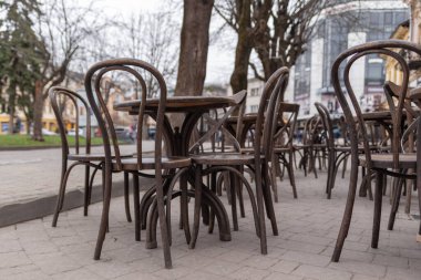 Ziyaretçisi olmayan bir sokak kafeteryasının sandalyeli ahşap masalar, salgın, karantina, kısıtlamalar