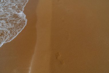 Kumsaldaki kumda ayak izleri. Seyahat ve tatil kavramı.
