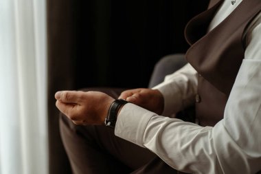 İş adamı koltukta otururken kol saatini kontrol ediyor.