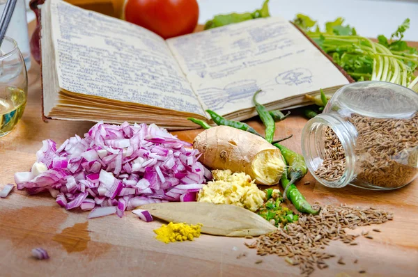 Mutfaktaki ahşap masada baharat ve sebzelerle çevrili tariflerle dolu notlar.