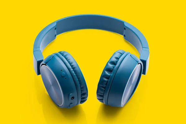 蓝牙蓝色耳机在黄色背景工作室产品特写设备 — 图库照片