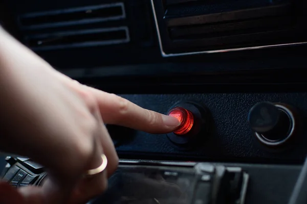 Black control panel in a Russian car with an emergency stop button. Female hand presses the emergency stop button