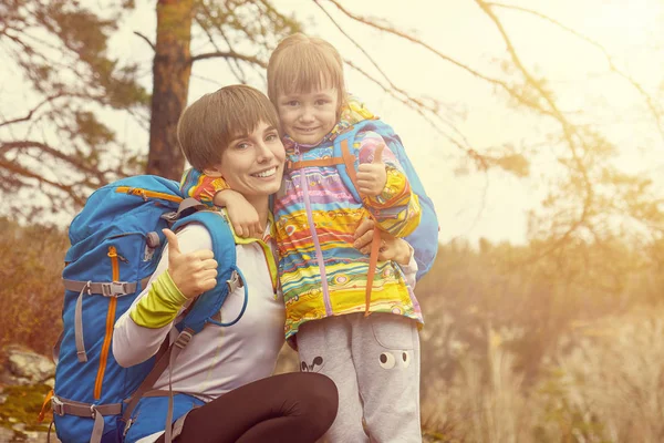 Sports family mother and child with backpacks thumb up
